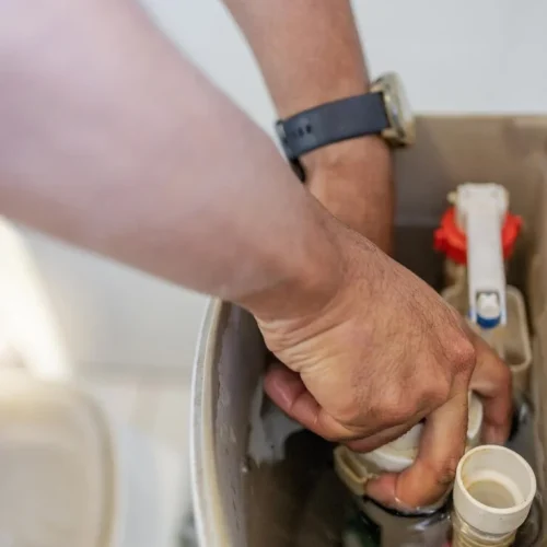 plumber repairing a fill valve inside a toilet tank